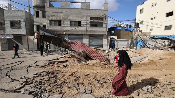 Une femme marche sur une route détruite au lendemain d'une frappe israélienne à Khan Yunis, dans le sud de la bande de Gaza, le 14 mai 2025.