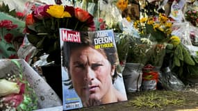 Un portait d'Alain Delon en Une du magazine Paris Match déposé parmi les fleurs devant la propriété de l'acteur décédé, le 21 août 2024 à Douchy, dans le Loirete 