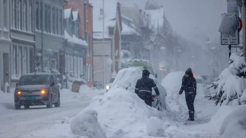 Des personnes retirent de la neige d'une voiture à Kristiansand, en Norvège, le 2 janvier 2024