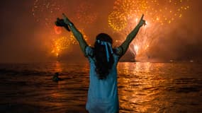 Sur cette photo prise le 31 décembre 2019, une femme célèbre le Nouvel An en regardant les feux d'artifice traditionnels sur la plage de Copacabana à Rio de Janeiro, au Brésil.
