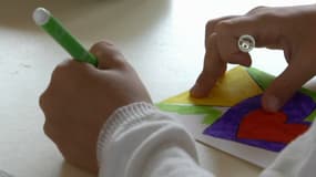 Un enfant dessine pour la fête des mères.